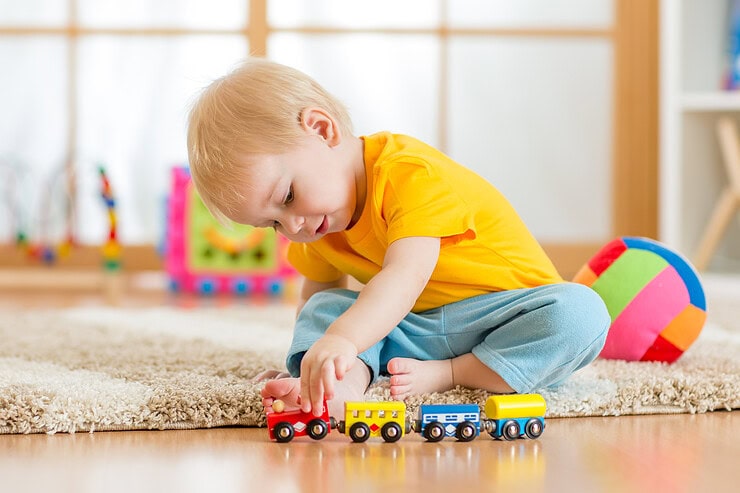 A small child plays with a toy train.
