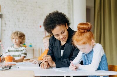 An adult helps a child in the classroom.