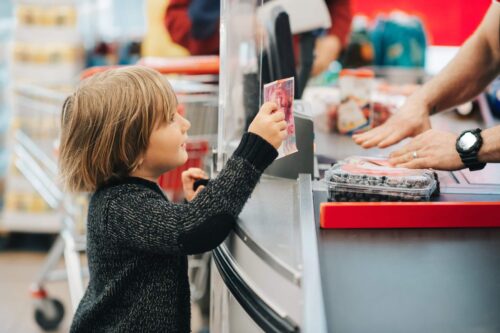 A boy is paying for groceries.