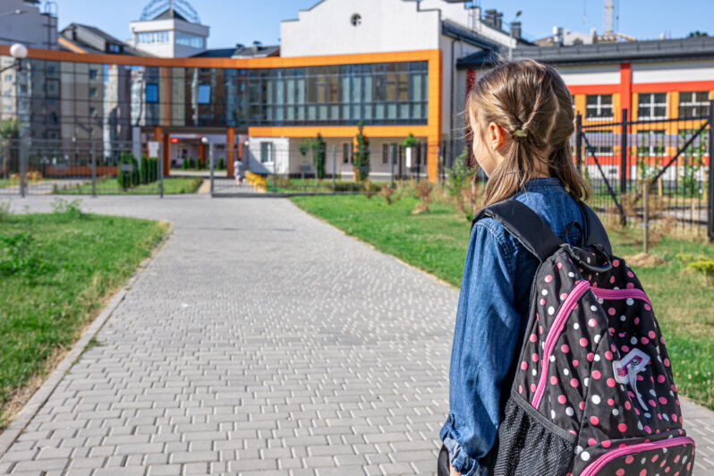 A child looks at their school building.