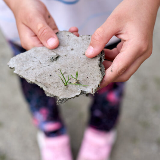 Young girl with a small block of soil in her hands.