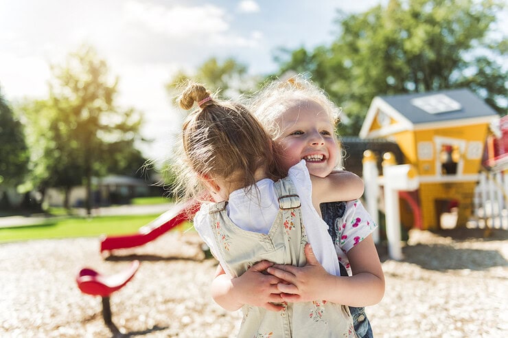 Two kids are hugging and playing on the playground.