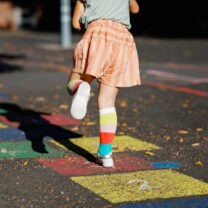 A girl plays hopscotch drawn on the ground with colorful chalk.