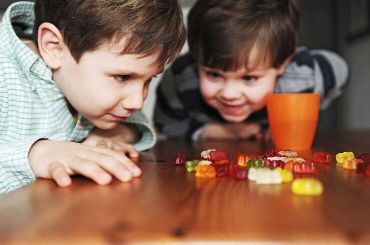 Two kids share candy on the table.
