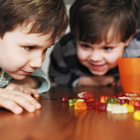 Two kids share candy on the table.