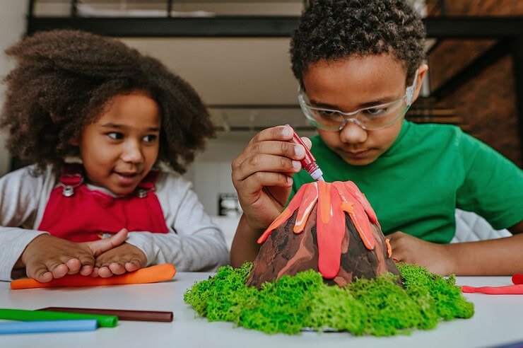 Two children make a volcano model.