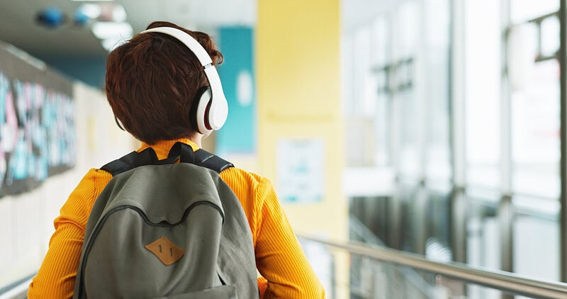 Un enfant marche dans son école en portant des écouteurs.