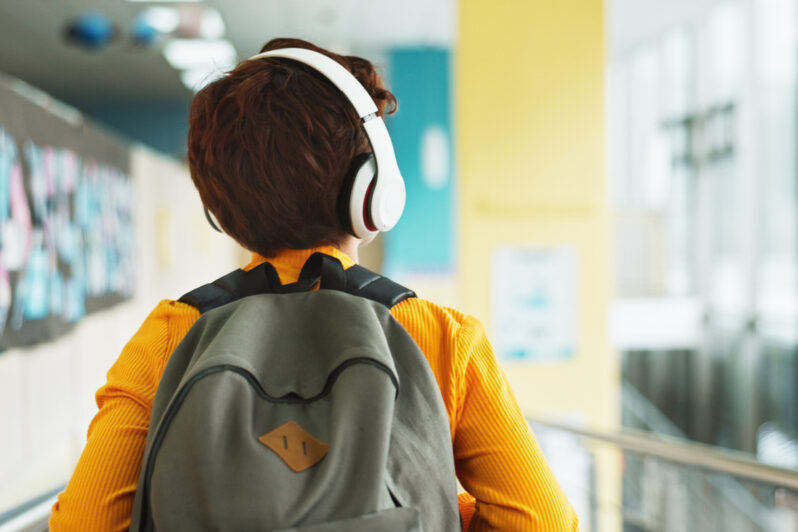 A child is walking in school wearing headphones.