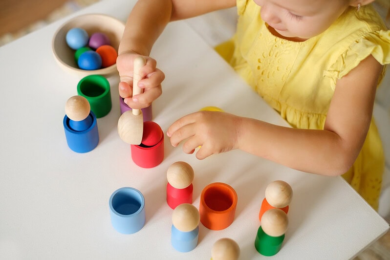 A child sorts coloured balls into cups.