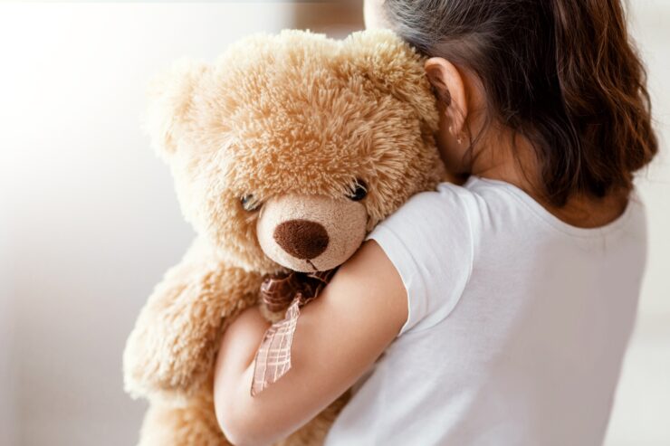 A child hugs a teddy bear.