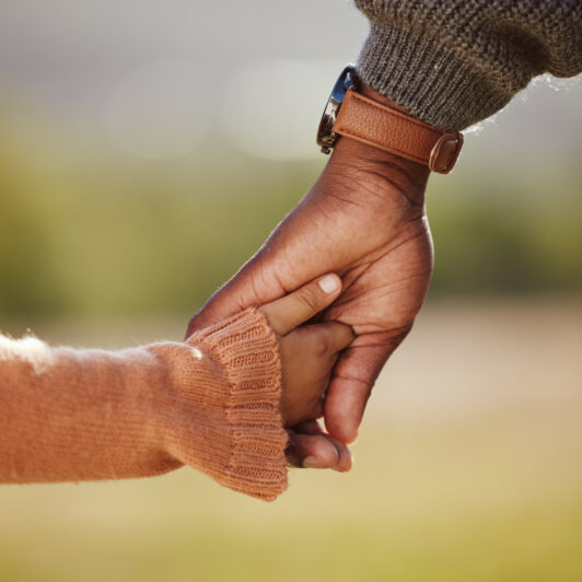 A child holds hands with her parent.