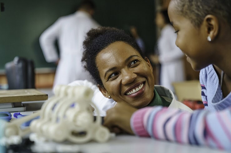 A teacher is smiling at her student in the classroom.
