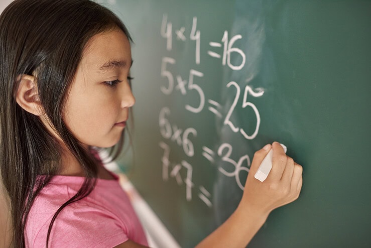 A child completes a maths equation on a chalkboard.