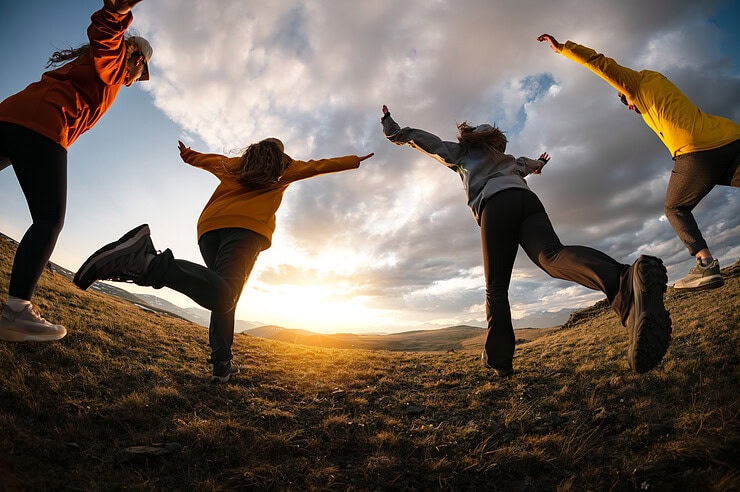 A group of teenagers running towards the sunset together.
