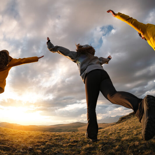 A group of teenagers running towards the sunset together.