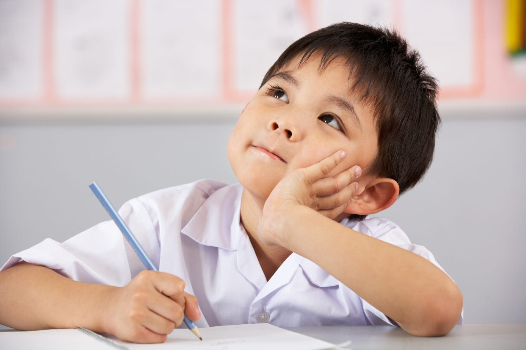A child is thinking while holding a pencil.