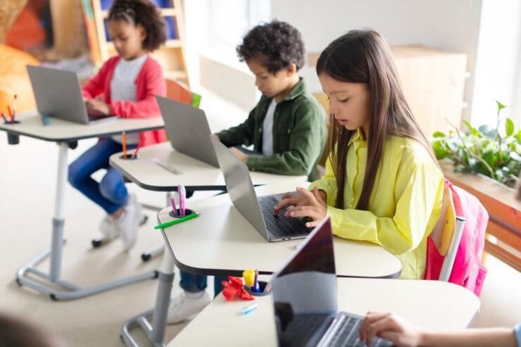 Children are using laptops in a classroom.