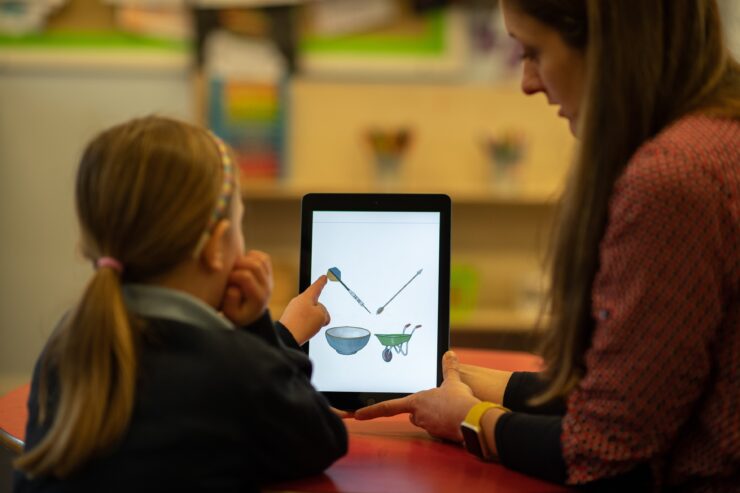 A child and an adult are using a tablet to learn.