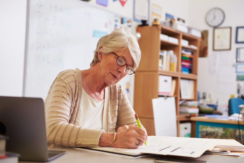 A teacher is writing in a notebook.