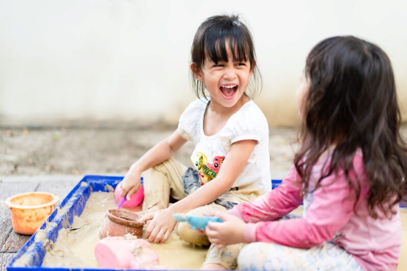 Two children are playing in a sandbox.