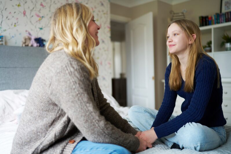 A mother and daughter are sitting together having a conversation.