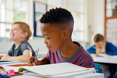 A boy writes in a notebook in the classroom.
