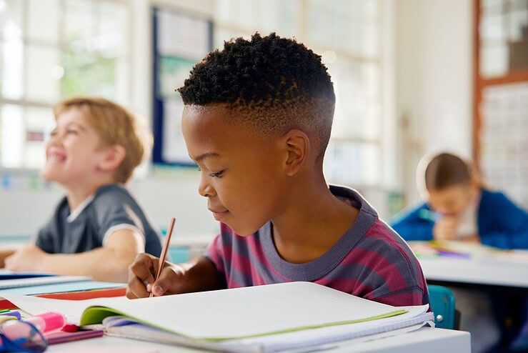A boy writes in a notebook in the classroom.