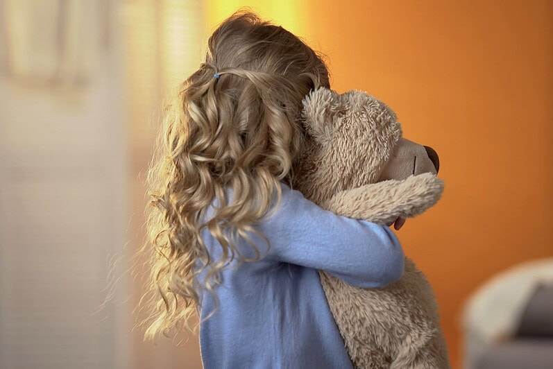 A child hugs a teddy bear.