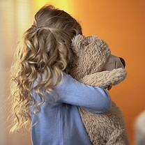 A girl is hugging her teddy bear.