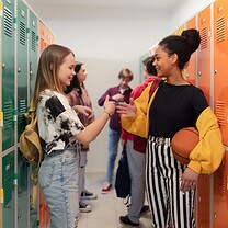 Two teens are greeting each other at school.