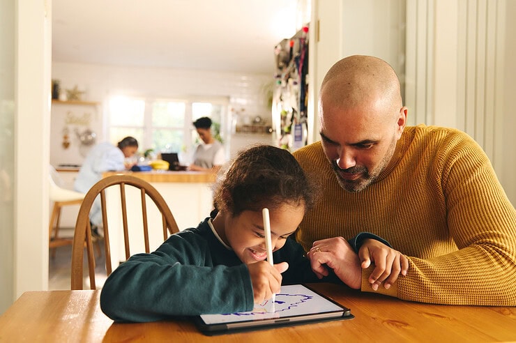 A parent and child work on a tablet together.