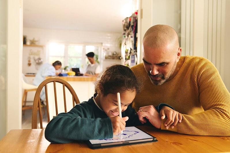 A parent and child work on a tablet together.