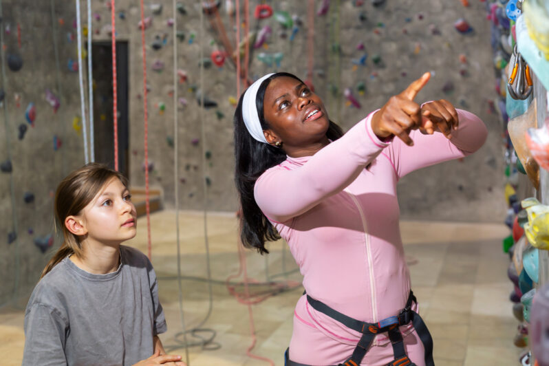 A mentor helps a child at the climbing wall.