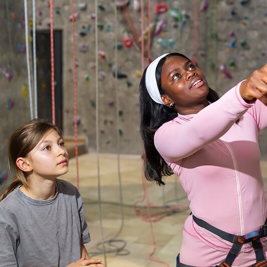 A mentor helps a child at the climbing wall.